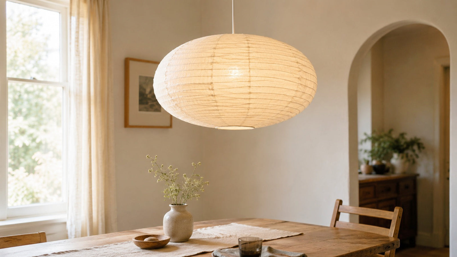 Large Saturn Oval linen fabric lantern lampshade in white beige, lit above a dining table in a warm, lived-in room